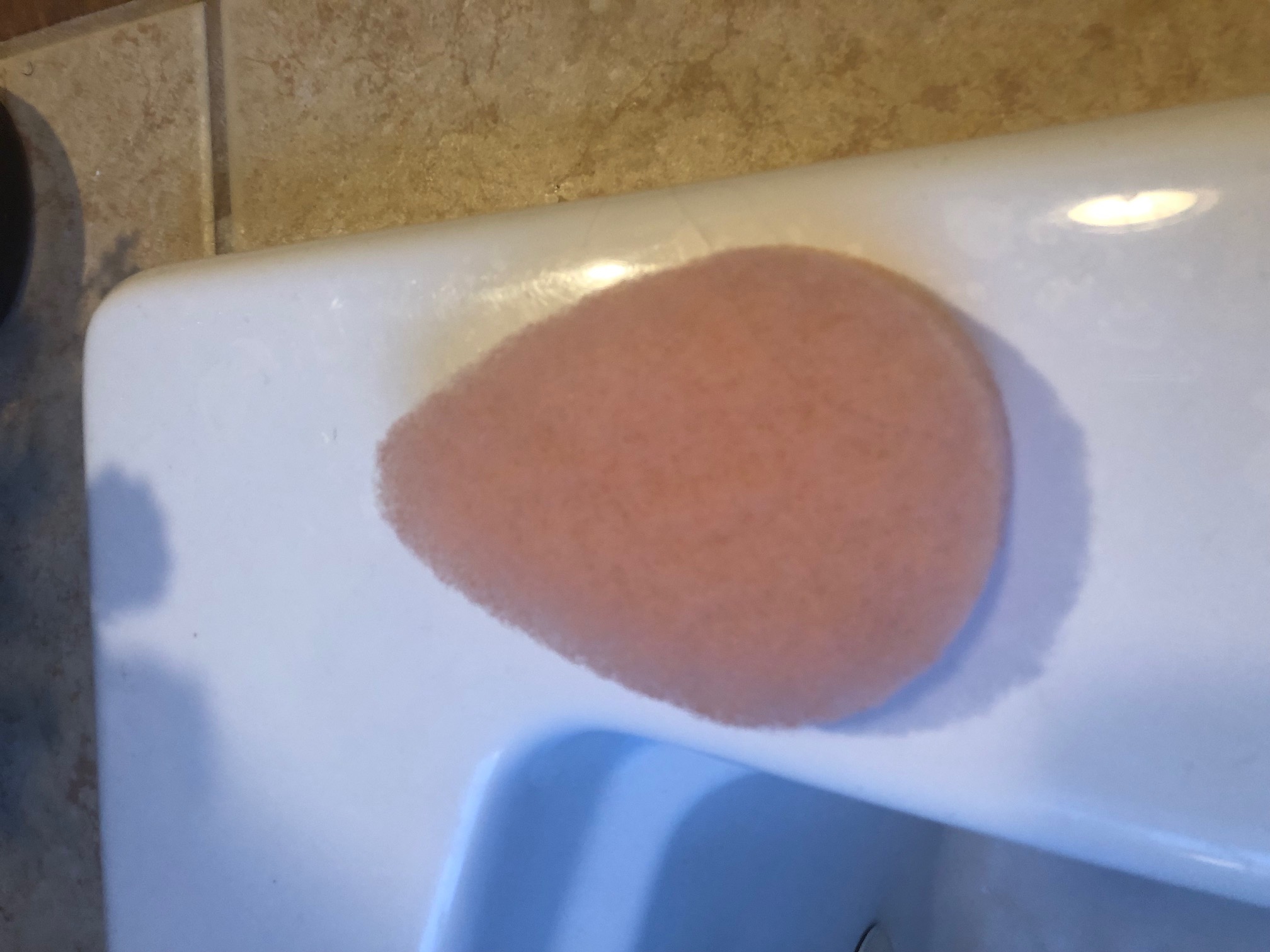 Pink Exfoliation Pad sitting on a White Enamel Bathtub Background